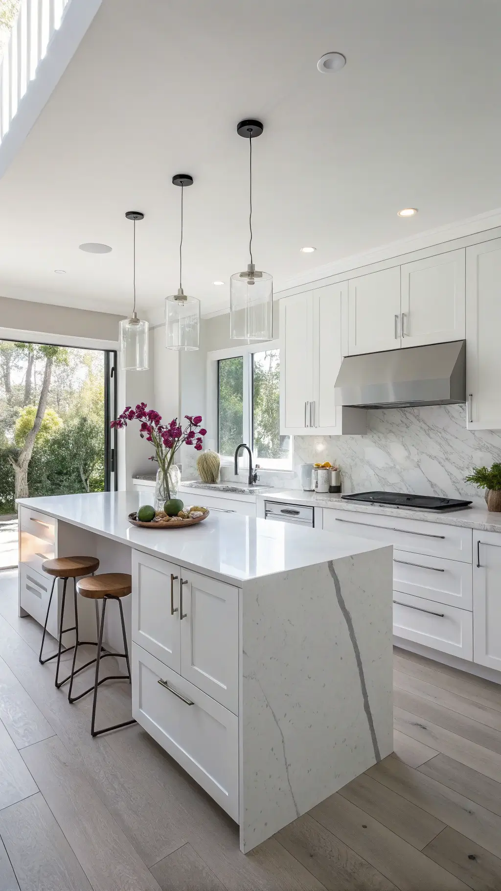 Minimalist, bright white kitchen with a waterfall quartz island, Shaker cabinets with invisible hardware, and enjoyably styled with a single orchid, white ceramics, and clear glass, captured in soft morning light through a wide-angle corner shot.