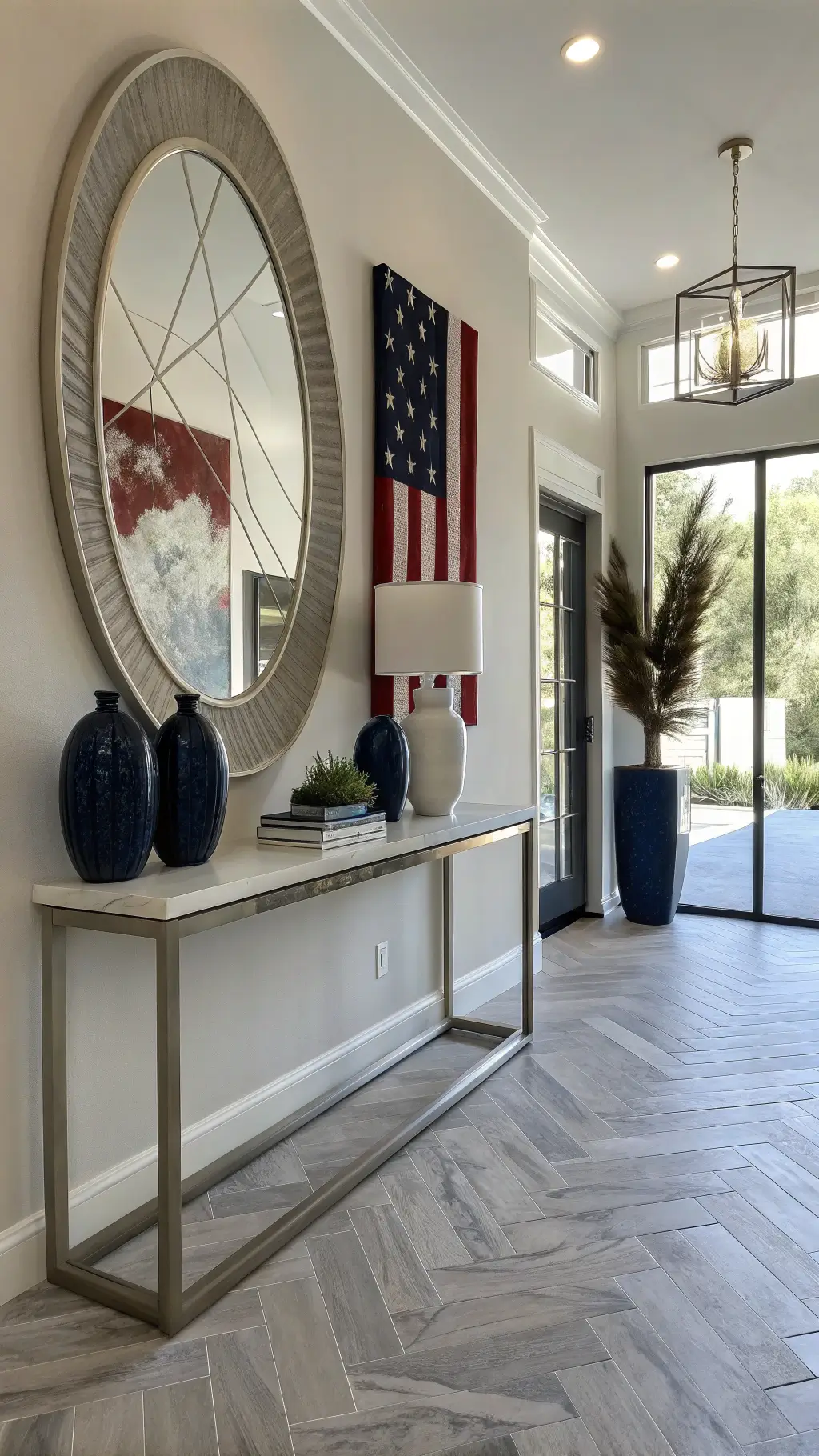 Minimalistic contemporary entryway with herringbone marble floors, brushed steel console table with geometric vases, oversized circular mirror with star detail, and abstract art in crimson and indigo, bathed in afternoon light.