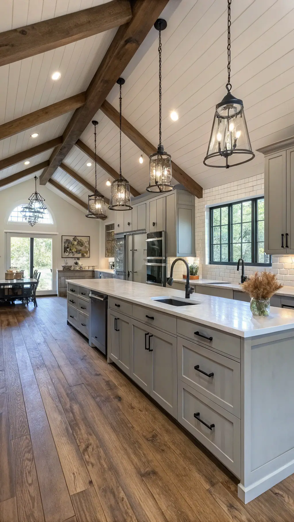Modern farmhouse kitchen with vaulted ceiling, dove gray cabinets, wide-plank oak floors, and contemporary pendant lights, capturing a balance of rustic and refined aesthetics.